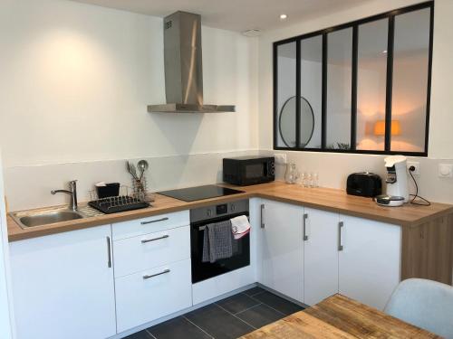 una cocina con armarios blancos y fregadero en Appartement T2 lumineux et cosy au calme proche du centre avec TV Netflix et Wifi, en La Rochelle