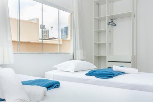 2 bedden in een witte kamer met een raam bij Casa confortável à 568m da praia de Ponta Negra in Natal