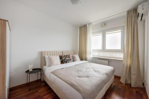 een witte slaapkamer met een bed en een raam bij Okopowa Joyful Apartment in Warschau