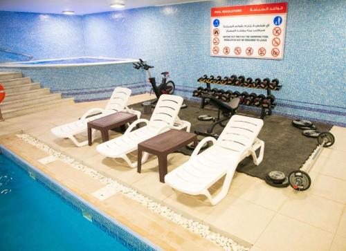 a swimming pool with white chairs and a table and a swimming pool at Bellevue Park Hotel in Taif