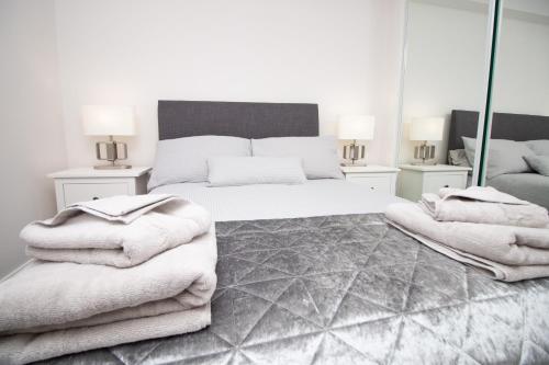 a white bedroom with a bed and mirrors at D'City Apartment, up to 6 guests in Dundee