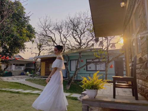 a woman in a white dress standing outside a house at Lacasa home&coffee Mộc Châu in Mộc Châu