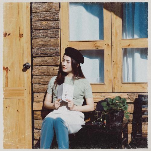 a woman sitting on a bench holding a book at Lacasa home&coffee Mộc Châu in Mộc Châu