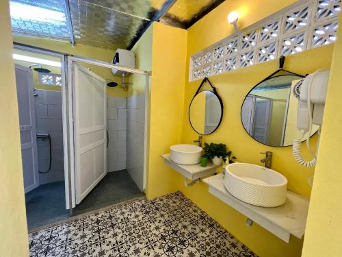 a yellow bathroom with two sinks and a mirror at Lacasa home&coffee Mộc Châu in Mộc Châu