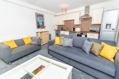 a living room with two couches and a kitchen at D'City Apartment, up to 6 guests in Dundee