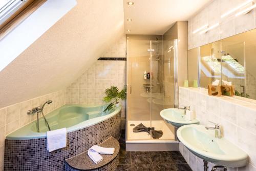 uma casa de banho com uma banheira, 2 lavatórios e um chuveiro em Waldblickwohnung für bis zu 5P mit Kamin und Sauna em Sebnitz