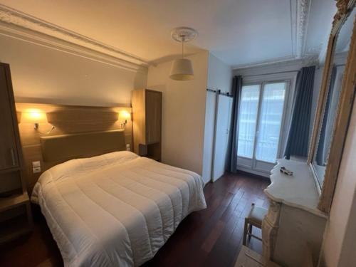 a bedroom with a white bed and a large window at Hotel Celtic in Paris