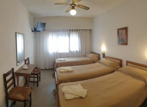 a hotel room with four beds and a window at Hotel Amancay in Mar de Ajó