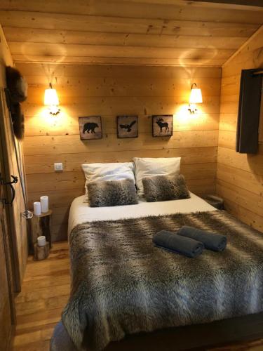 1 dormitorio con 1 cama en una cabaña de madera en La Cabane du Trappeur, en Ore