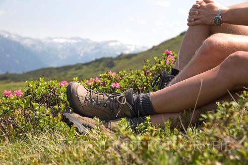 two people sitting in the grass with their feet in flowers at Ferienwohnungen Monika Winter in Kleinarl