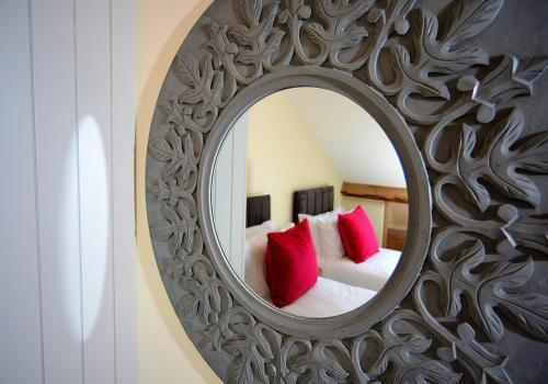 a mirror in a room with a bed with red pillows at Pippin Lodge Lytham in Lytham St Annes