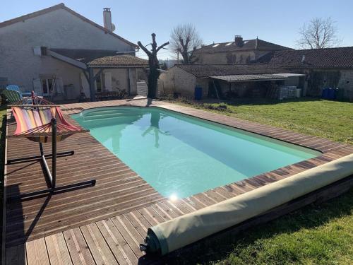 une grande piscine sur une terrasse en bois dans l'établissement Maison charentaise avec piscine chauffée, jardin privé et proche commerces, idéale pour couples - FR-1-653-228, à Aunac