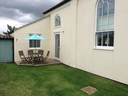 a patio with a table and a blue umbrella at Acorn Chapel - Beautiful Converted Chapel in Norwich