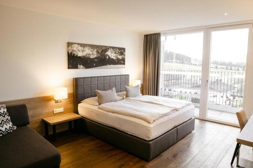 1 dormitorio con cama, sofá y ventana en Sentido alpenhotel Kaiserfels, en Sankt Johann in Tirol