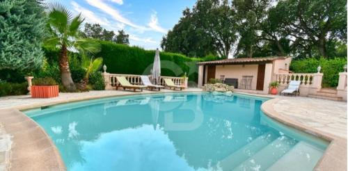 uma piscina num quintal com cadeiras e uma casa em Domaine des Tuilières avec piscine em Vallauris