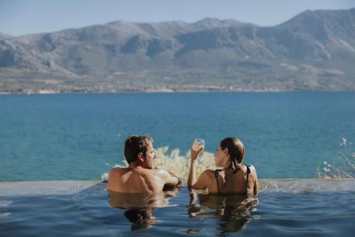 a man and a woman sitting in a swimming pool in the water at Amethyst Selene Paleros Couple's Hideaway in Paleros