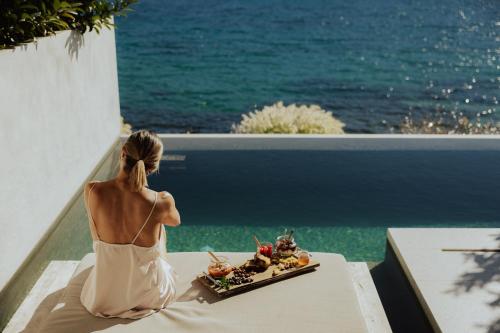 a woman sitting on a ledge looking out at the ocean at Amethyst Selene Paleros Couple's Hideaway in Paleros