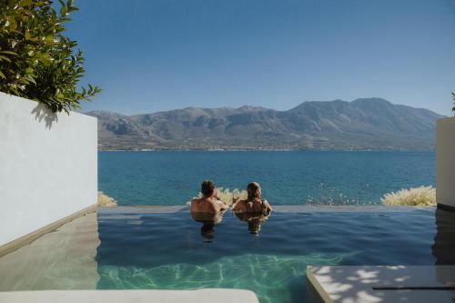 two people sitting in a swimming pool in the water at Amethyst Selene Paleros Couple's Hideaway in Paleros