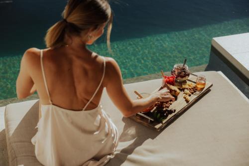 a woman sitting at a table with a plate of food at Amethyst Selene Paleros Couple's Hideaway in Paleros