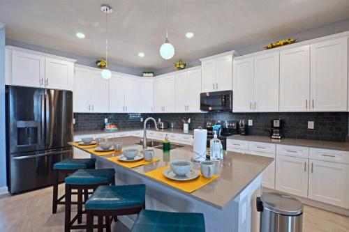 a kitchen with white cabinets and a kitchen island with stools at Amazing 6BR Villa @ Storey Lake Resort Near Disney in Kissimmee