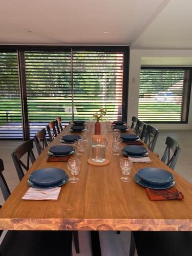 a long wooden table with chairs and plates and glasses at Magnifique lodge dans la forêt de Fontainebleau in Arbonne-la-Foret