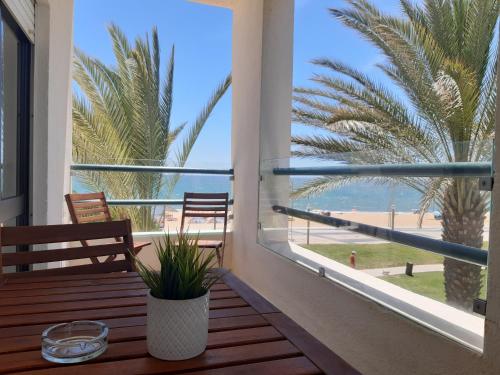 a balcony with a view of the beach and palm trees at Apartamento Kélyfos Beach by feriascomsol in Quarteira
