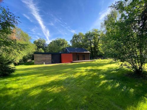 a building in the middle of a grassy field at Magnifique lodge dans la forêt de Fontainebleau in Arbonne-la-Foret