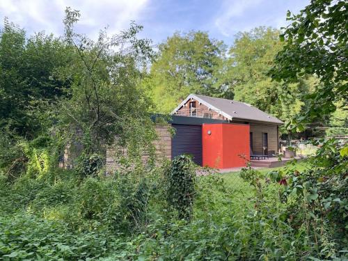 a small house with a red door in a field at Magnifique lodge dans la forêt de Fontainebleau in Arbonne-la-Foret