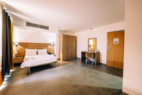 Cette chambre comprend un lit et un bureau. dans l'établissement Primera Hotel, à San Pawl il-Baħar