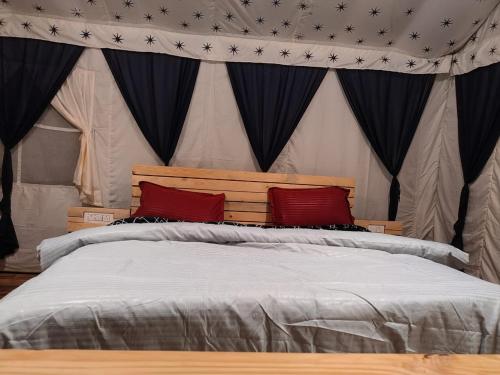 een slaapkamer met een groot bed met rode kussens bij Imilia Camps in Bir