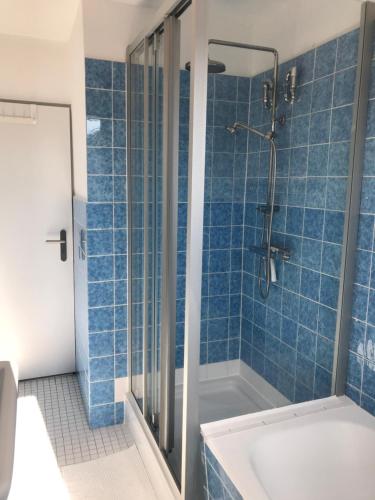 y baño de azulejos azules con ducha y bañera. en Ferienwohnung Sonnendeck, en Eckernförde
