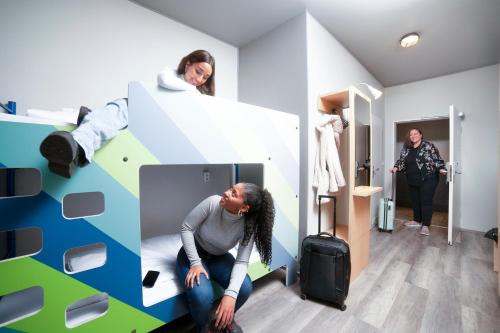 a woman sitting on a bed with a suitcase in a room at a&o Wien Stadthalle in Vienna