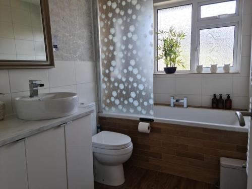 a bathroom with a sink and a toilet and a tub at Charming spacious 2 bed apartment in quiet area in Exhall