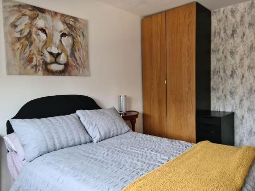 a bedroom with a bed and a painting of a lion at Charming spacious 2 bed apartment in quiet area in Exhall
