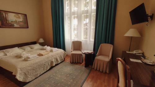 1 Schlafzimmer mit einem Bett, 2 Stühlen und einem Fenster in der Unterkunft Batthyány Kastélyszálló in Zalacsány
