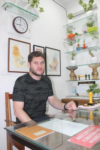 a man sitting at a table in a room at CHOUDHARY WHITE HOUSE Udaipur in Udaipur