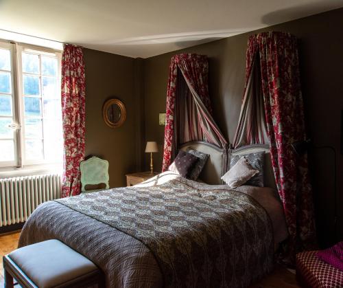 a bedroom with a large bed with red curtains at Château de Pramenoux in Lamure-sur-Azergues