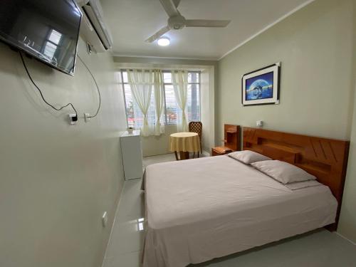 1 dormitorio con 1 cama y TV en la pared en A&A HOTEL, en Iquitos