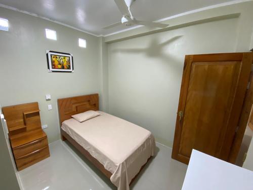 a small bedroom with a bed and a wooden door at A&A HOTEL in Iquitos