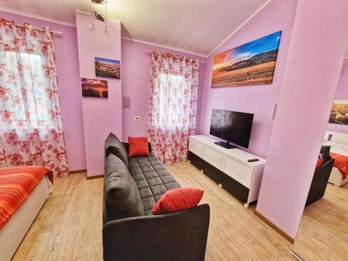 a purple living room with a couch and a tv at W a n d e r l u s t - casa con piscina riscaldata ad uso esclusivo - Marche in Rustico