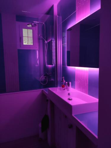 a purple bathroom with a sink and a mirror at Atelier des sens 89 in Évry