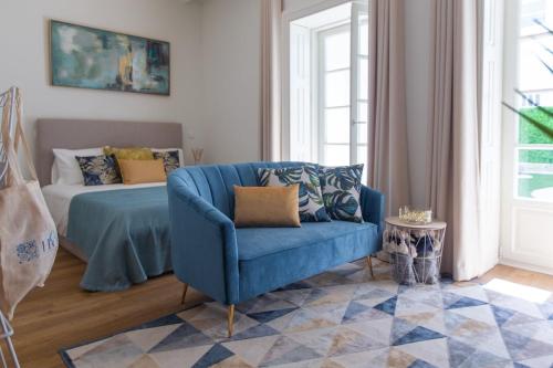 - un salon avec un canapé bleu et un lit dans l'établissement Charm Luxury House, à Porto