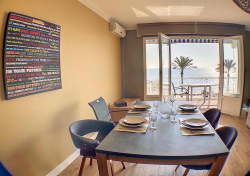 une salle à manger avec une table et des chaises ainsi qu'un menu mural dans l'établissement Charmant 2 pièces FACE à la MER- Cagnes sur Mer, à Cagnes-sur-Mer