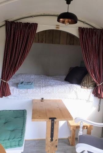 a room with a bed and a wooden table at Pipowagen Eldikse Blauwe in Lienden