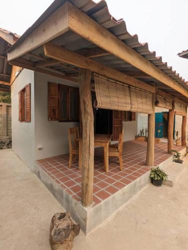 Casa con patio con mesa y techo en Maison moderne proche du centre-ville en Luang Prabang