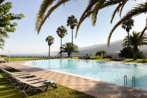 a swimming pool with lounge chairs and palm trees at Hotel Las Águilas Tenerife, Affiliated by Meliá in Puerto de la Cruz