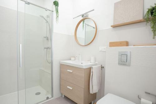 La salle de bains blanche est pourvue d'un lavabo et d'une douche. dans l'établissement Duplex Mandelieu, à Mandelieu-la-Napoule