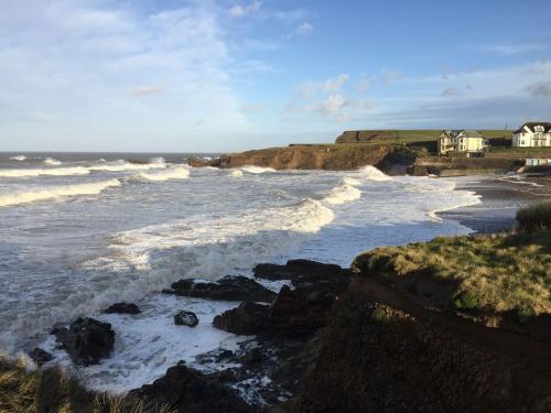 a view of the ocean with waves crashing on the rocks at The Milking Parlour in Beaworthy