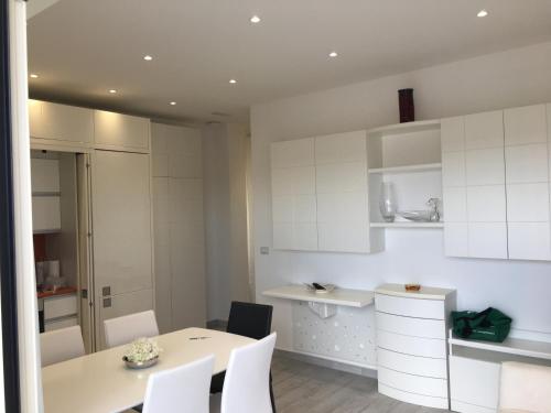 a kitchen with white cabinets and a table and chairs at Bianco&Nero 141 Apartament in Margherita di Savoia
