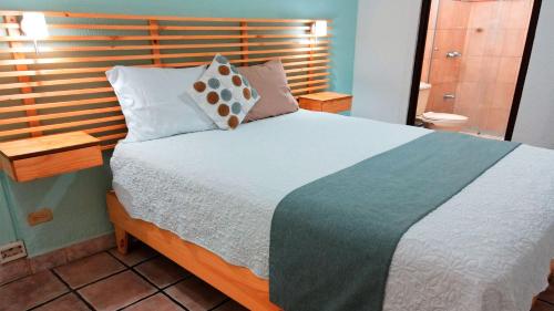 a bedroom with a large bed with a wooden headboard at Trebol Amarillo Bed & Breakfast in Escazu